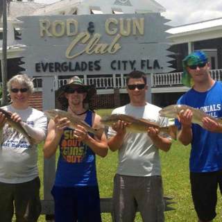 Four guys holding their fish in front of Rod & Gun Club