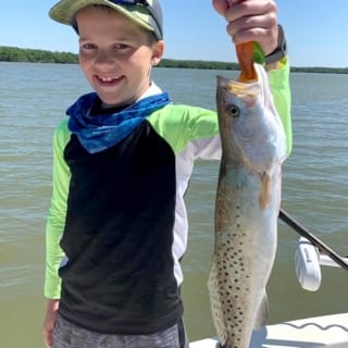 A young boy holding up a fish